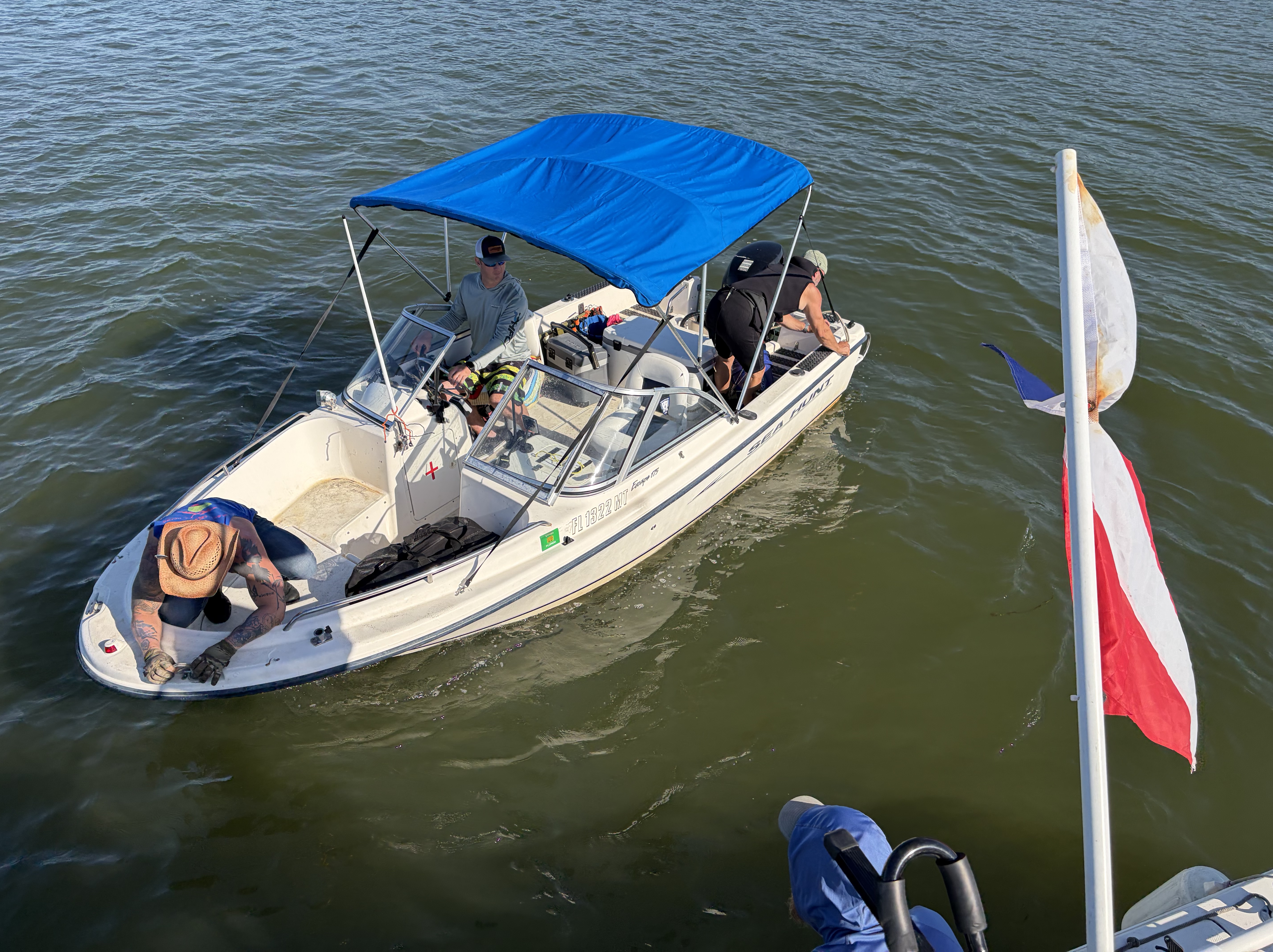 Sea Hunt 18 with crew aboard preparing for a dive, dock flags flying