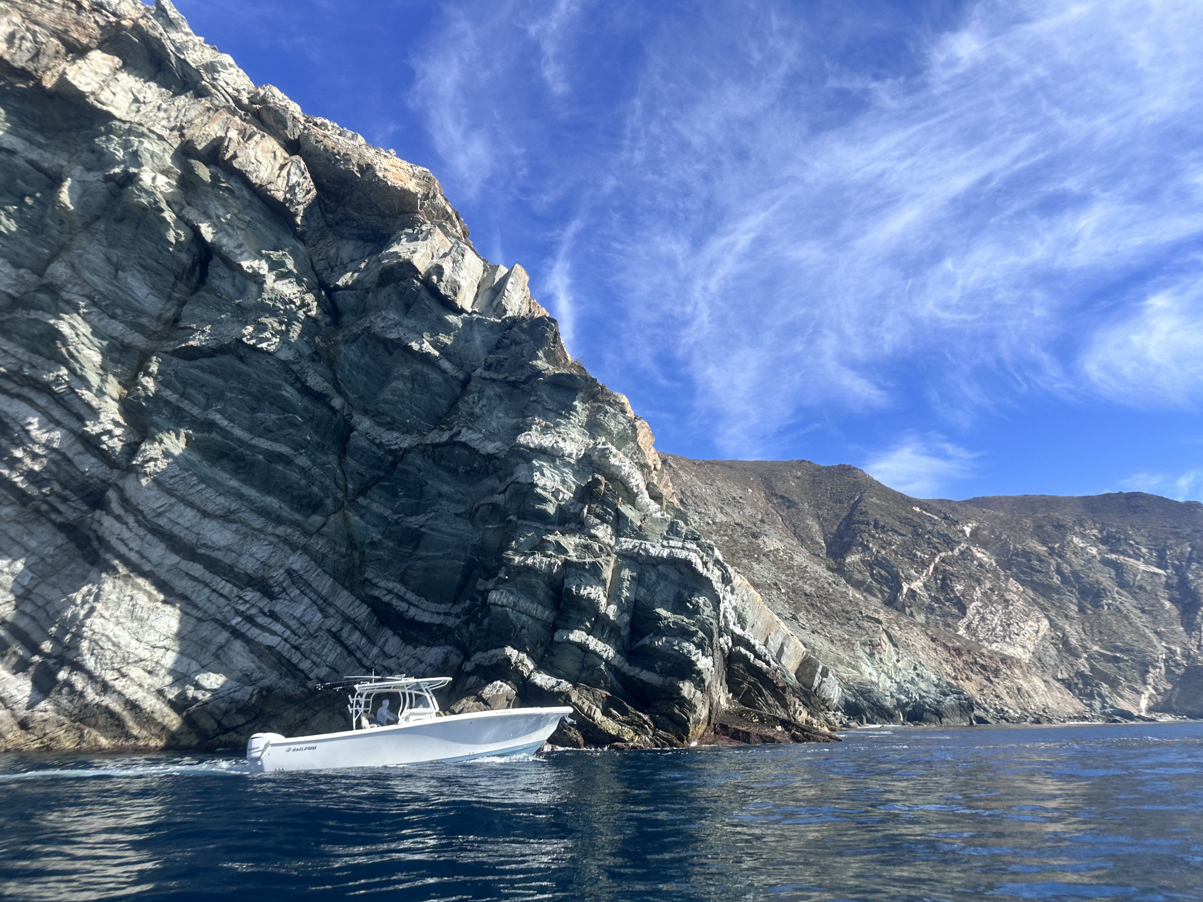 Sailfish 32 underway along a rocky coastline